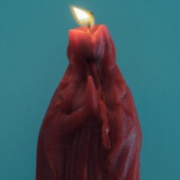 Red candle of Virgin Mary against teal background